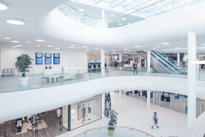 Inside view of the extension of the shopping center. The search for curved shapes by the architects resulted in curved glazed parapets that allow light to enter the building's central spaces directly from the large steel and glass roof at the top.
